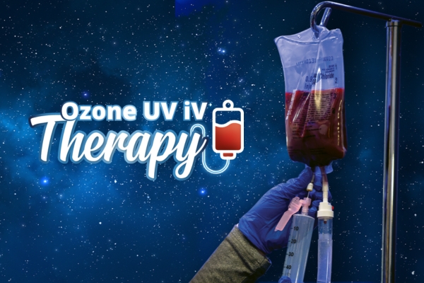 A medical professional wearing blue gloves holds an IV bag connected to tubing in a hanging infusion setup